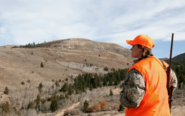 Female hunter in high visibility gear looking over bluffs
