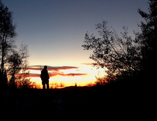 Silhouette of hunter and woods at sunrise