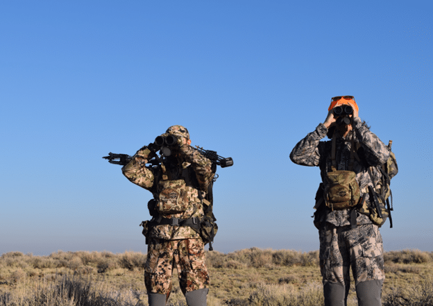 Two hunters looking into the distance with binoculars