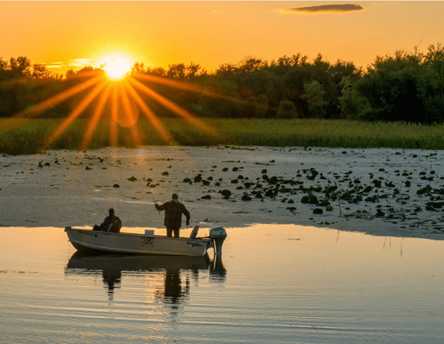 Fisherman near shore fishing at sunset