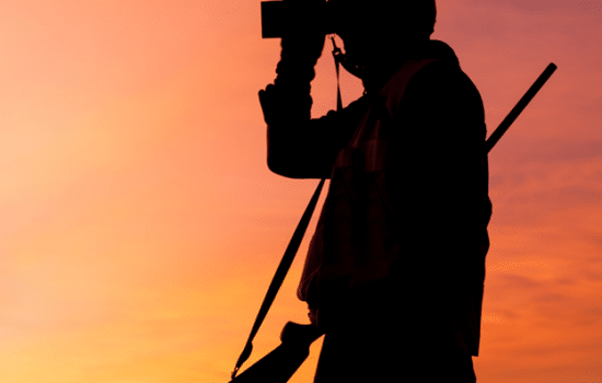 Silhouette of hunter with binoculars at dawn